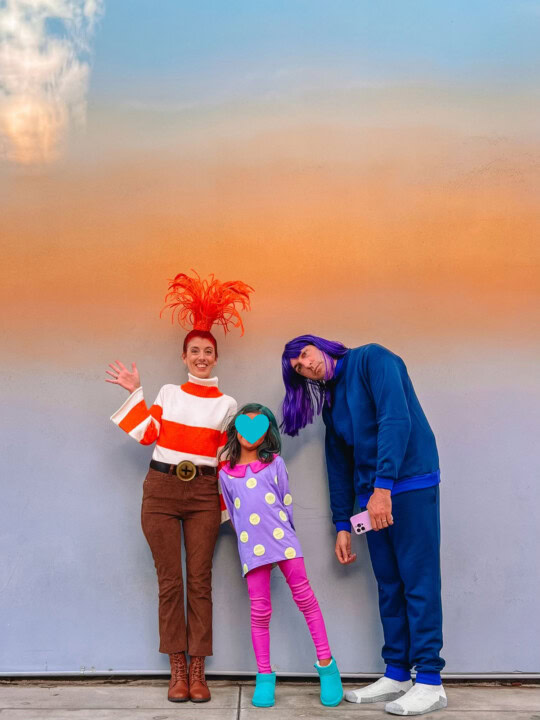 Family wearing Inside Out 2 costumes in front of ombre wall