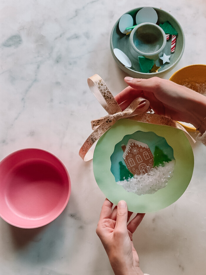 hands holding paper plate snow globe