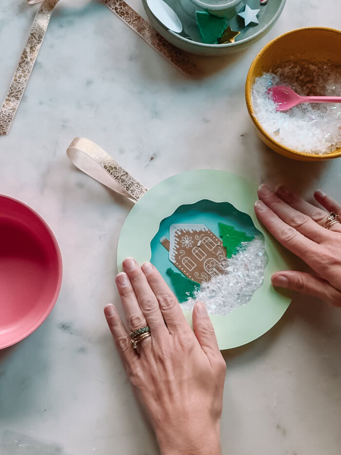 completing paper plate snow globe