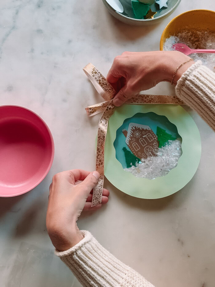 adding bow to paper plate snow globe