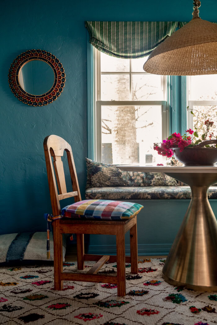 Wood dining chair in blue dining room with round mirror