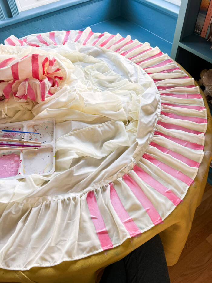 painting pink stripes on white skirt on table
