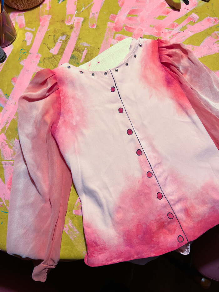 pink painted shirt laying on yellow table